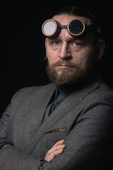 charismatic man in a classic suit and steampunk goggles on a black background stylish Portrait