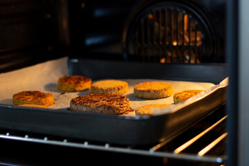 Healthy vegan burger on baking paper cooked in the oven. Grilled plant based burger patties. Veggie burger with chickpea, spinach and carrots for a diet burger. Vegan food and protein product.
