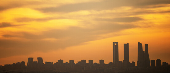 Panoramic view where the sun silhouettes the skyscrapers of Madrid's skyline, known as the 'Four Towers Business Area', during sunset