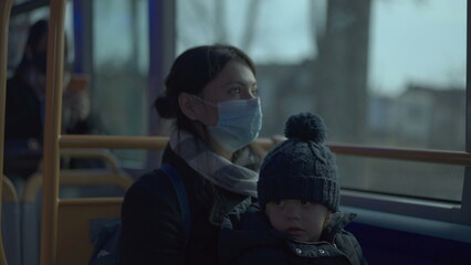 Mother wearing covid-19 face mask with toddler inside bus public transportation