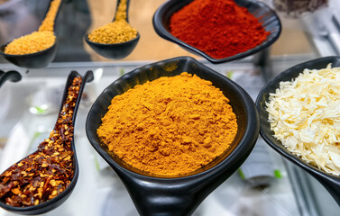 Turmeric powder spice in black bowl and other spices in the market. Selective focus.