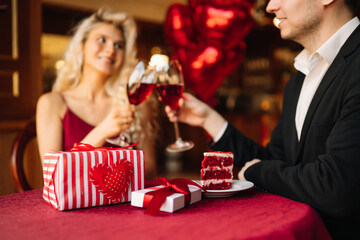 Surprise for Valentine's day. Young couple celebrating Valentine's Day  with glass of red wine. Romantic day together.