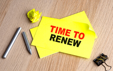 TIME TO RENEW text on yellow sticky on wooden background