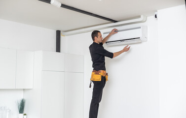 Male technician cleaning air conditioner indoors