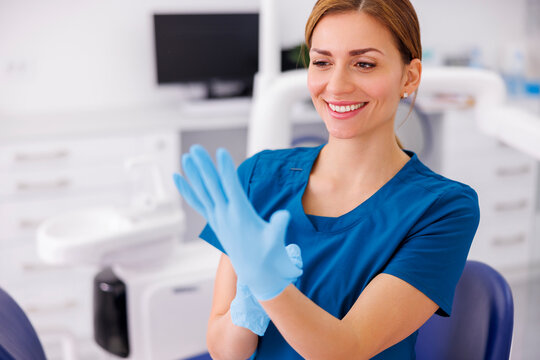Female doctor putting on protective latex gloves