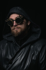 A man in a hood, wearing vintage steampunk goggles looking at the camera close-up