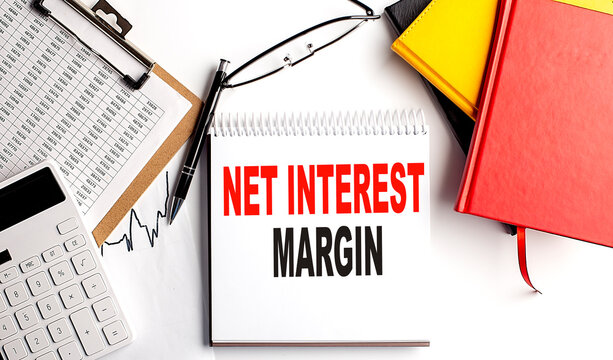 NIM - Net Interest Margin text on notebook with clipboard and calculator on white background