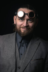 Obraz premium charismatic man in a classic suit and steampunk goggles on a black background stylish Portrait
