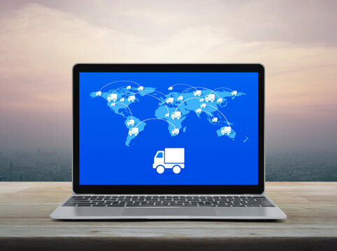 Delivery truck icon with connection line and world map on laptop computer screen on table over office city tower at sunset sky, vintage style, Elements of this image furnished by NASA