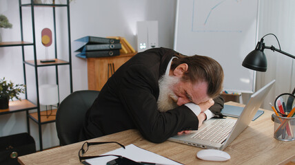 Bored sleepy old businessman worker working on laptop computer, yawning, leaning on hand falling asleep at office. Exhausted tired freelancer workaholic senior man. Employment, occupation, workless