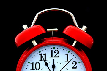Red alarm clock on a black background.