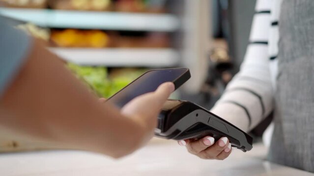 Customer using wireless digital payment on smartphone at the supermarket. 
