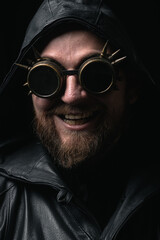 A man in a hood, wearing vintage steampunk goggles looking at the camera close-up