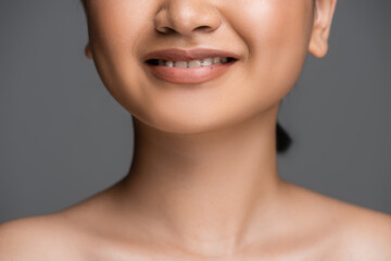 Obraz premium Cropped view of young woman with naked shoulders smiling isolated on grey.
