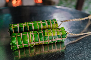 Making (wrapping) Tet Cake (Bánh Tét), the Vietnamese lunar new year Tet food outdoor with old woman hands and ingredients. Closed-up.