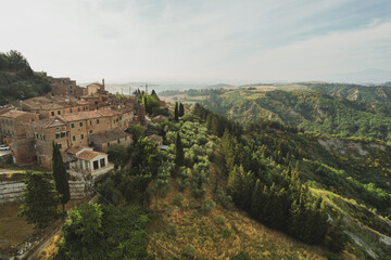 Fototapeta na wymiar Small village of Chiusure on top of the hill surrounded by Karst cliffs landscape photographed with a drone. Toscana, Tuscany, Asciano, province of Siena in Italy with a little mud road 06.16.2021