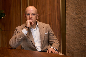 Modern man in a beige jacket sits in stylish office