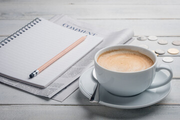 Black cup of coffee, notebook, newspaper and laptop on the table, morning news. get ready for work in the morning