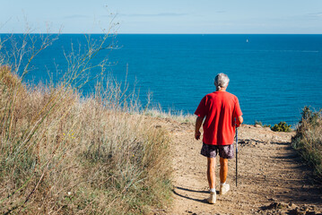 Un homme retraité marchant au bord de la mer. Un homme âgé marchant sur le littoral. Un vieil homme en vacances. Senior dans le sud de la France