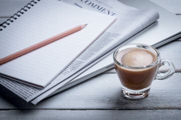 Black coffee cups, notebooks, newspapers and laptops are placed on the table. Morning news, morning preparation.