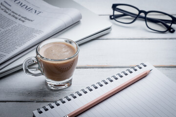 Black coffee cups, notebooks, newspapers and laptops are placed on the table. Morning news, morning preparation.