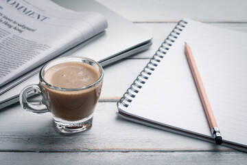 Black cup of coffee, notebook, newspaper and laptop on the table, morning news. get ready for work in the morning