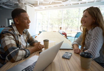 Two happy colleagues talking in office lobby