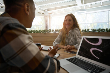 Happy pretty woman talking to her male friends in office lobby
