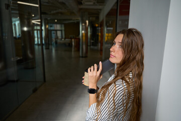 Young woman standing and holding coffee, phone