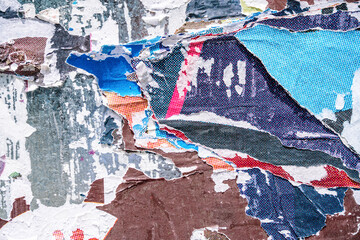 Torn paper collage background on an old poster on a street wall. Texture and surface of torn paper.