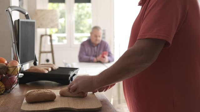 Man Preparing Breakfast While His Gay Couple Using Phone At Home