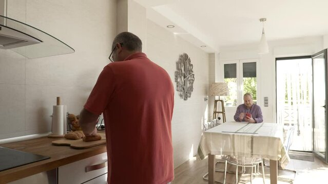 Adult Man Preparing Breakfast While His Gay Couple Using Phone At Home