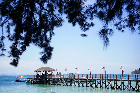 Manukan Pier in Sabah, Malaysia viewed from the shore through Casuarina equisetifolia branches                                