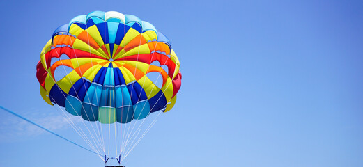 Rainbow parasailing balloon flying high in the sky on a clear bright day                          