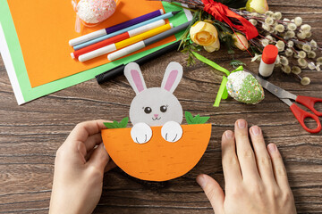 A child is holding an Easter card gift Easter bunny. Handmade. Project of children's creativity, handicrafts, crafts for kids.
