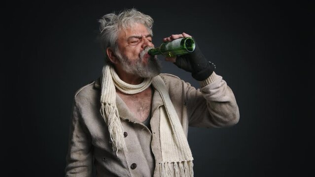 Portrait of adult man drinking beer with black isolated background behind. Close-up view of poor, homeless, caucasian senior addicted to alcohol. High quality 4k footage