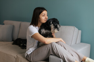 Beautiful caucasian woman with vitiligo hugging her dog miniature schnauzer breed on the couch at home. Friendship concept