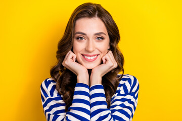 Photo portrait of attractive young woman fists touch face adorable admire dressed stylish striped look isolated on yellow color background