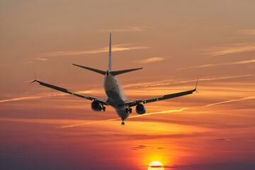 A plane in a picturesque golden red sky at sunset. Copy space. Selective focus.