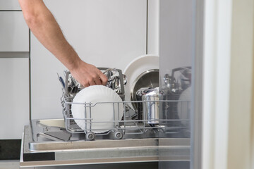 Dishwasher open and a person removing the washed dishes. Concept of saving water and time in daily domestic activities.