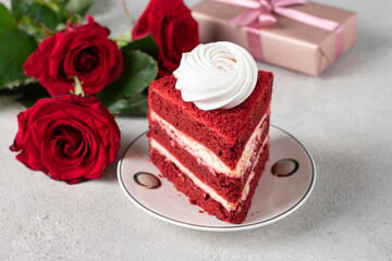 Piece of Red Velvet cake, roses and gift for Valentines Day or birthday on gray background