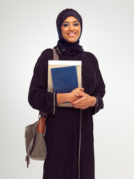 Portrait, muslim and education with a student woman holding books in studio on a gray background for learning. Islam, university and study with an islamic female at college to study on a scholarship