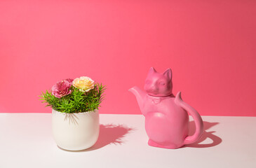 Pink porcelan teapot in a cat form and vase with flowers. Spring concept
