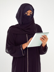 Woman, tablet and muslim typing with hijab for online islamic research against grey studio background. Female isolated standing holding touchscreen with scarf reading news on islam, arabic or culture