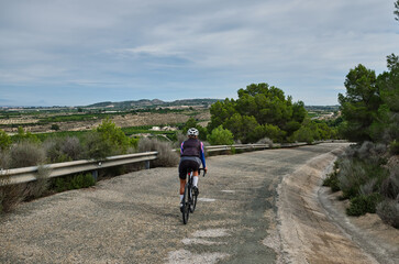 Obraz premium woman cyclist riding a gravel bike with a view of the mountains, Murcia region of Spain