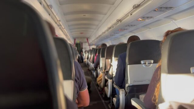Back of plane corridor aisle. Passenger seated inside airplane traveling in flight