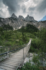 Fototapeta na wymiar Hängebrücke in grüner Landschaft in den Alpen mit Felsen in Berchtesgaden.