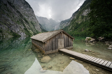 Fototapeta na wymiar Hütte mit Steg bei Regen an einem See im Nationalpark in den Bergen.