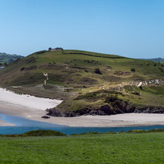 Plant-covered dunes on a sunny spring day. Green hills. Seaside Irish landscape. The beauty of nature.