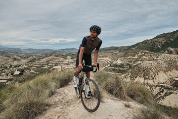 Naklejka na ściany i meble Men riding gravel bike on gravel road in mountains with scenic view in Murcia region, Spain